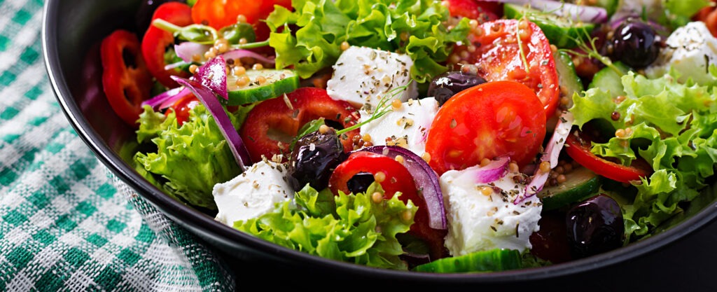 Healthy food. Greek salad with cucumber, tomato, sweet pepper, lettuce, red onion, feta cheese and olives